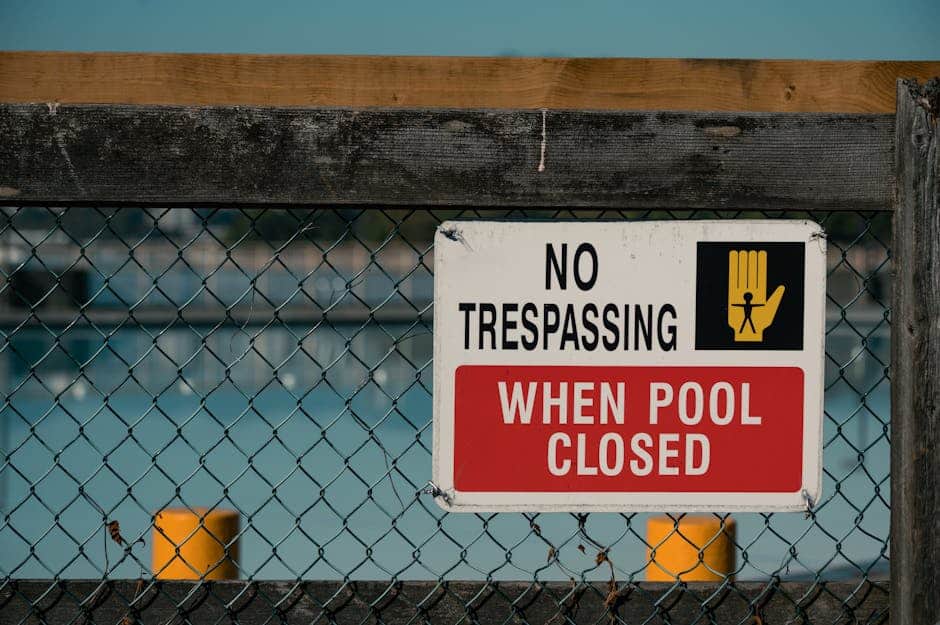 A 'No Trespassing' sign on a chain link fence at a closed swimming pool, ensuring safety and security.