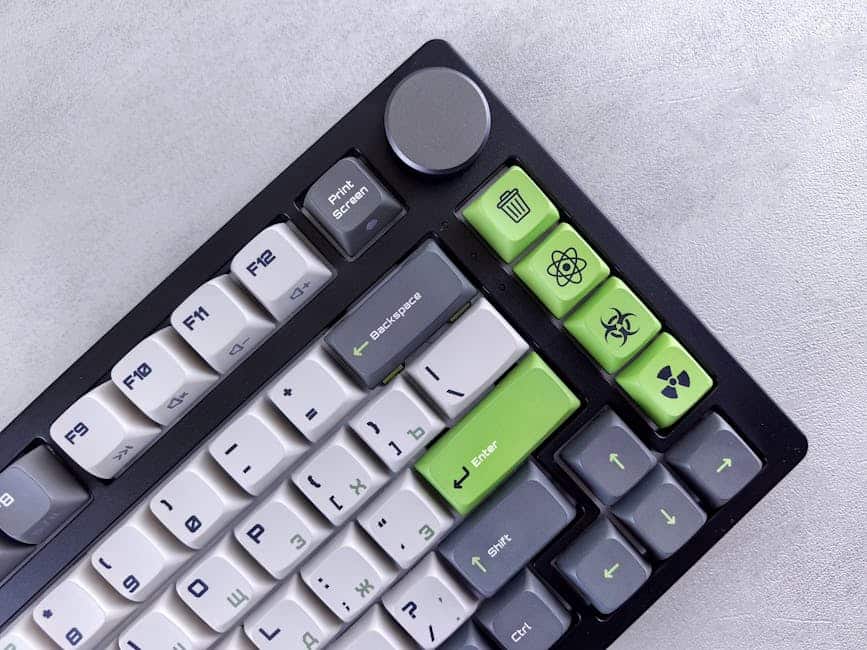 Detailed view of a custom mechanical keyboard with green and gray keys in a studio setting.