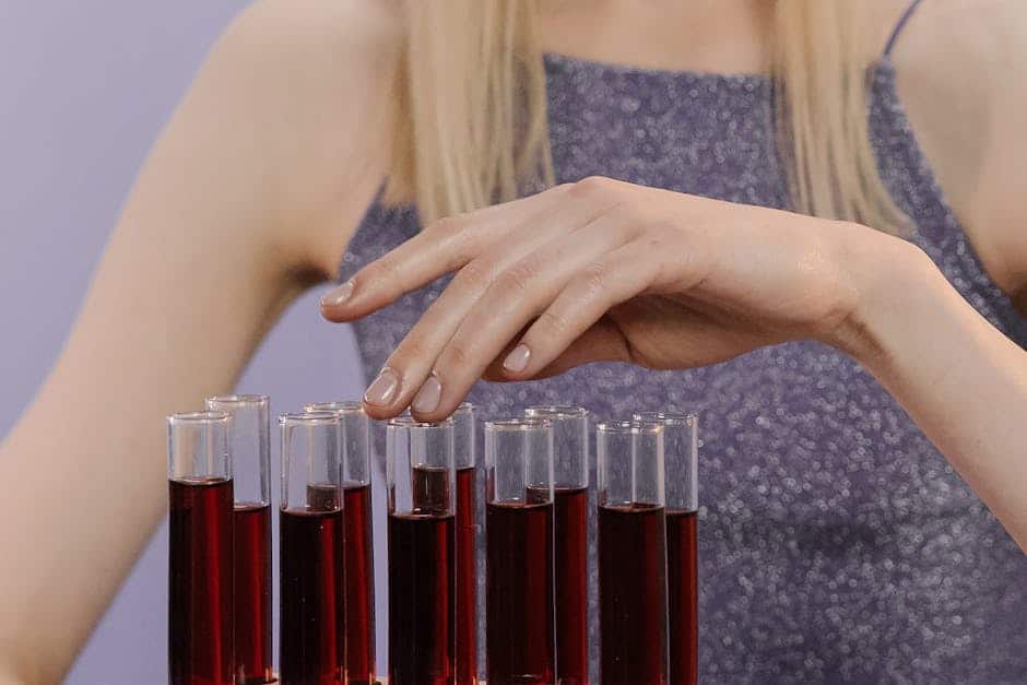 Close-up of a woman carefully handling test tubes filled with a red liquid in a lab setting.
