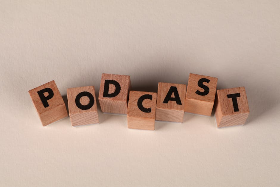 Wooden blocks spelling 'PODCAST' on a neutral background, symbolizing audio content creation.
