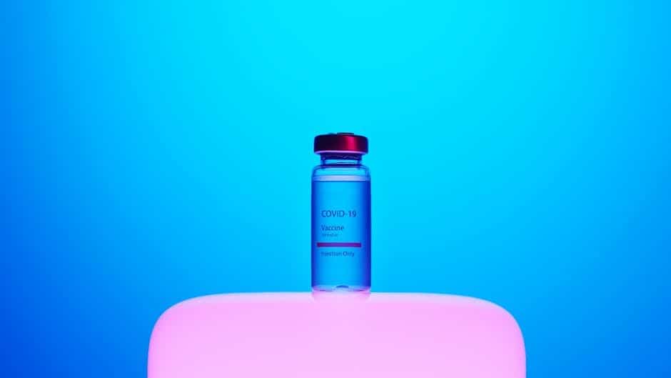 Blue background with a COVID-19 vaccine vial signifying health and prevention.
