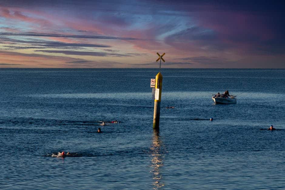 Peaceful scene of swimmers and a boat at sunset on Williamstown Beach, Australia.
