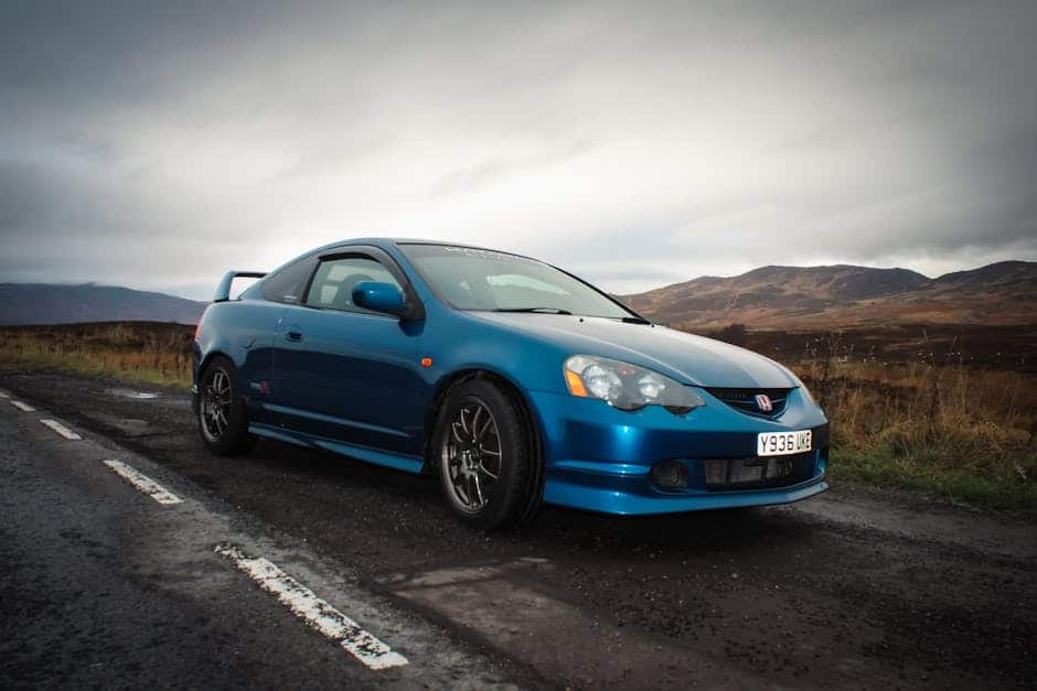 A vibrant blue Honda Integra parked roadside in the scenic Scottish Highlands, showcasing its sleek design.