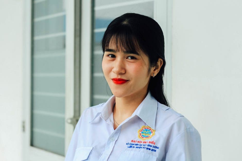 Portrait of a smiling woman in a white school uniform indoors with a confident expression.