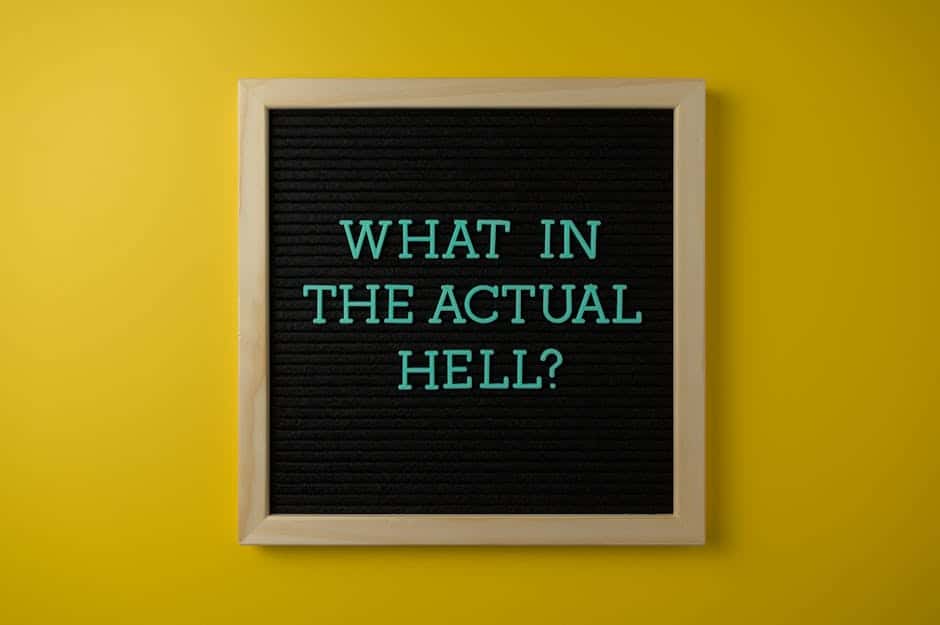 Letter board with humorous quote 'What in the actual hell?' on a vibrant yellow backdrop.