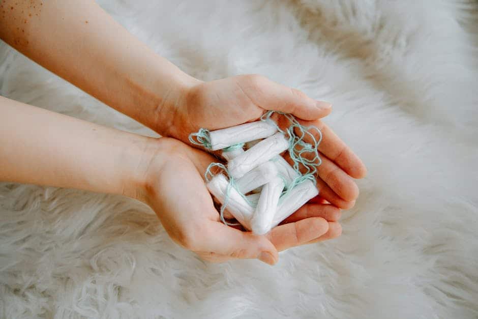A woman's hands gently hold a bunch of tampons against a soft white background.