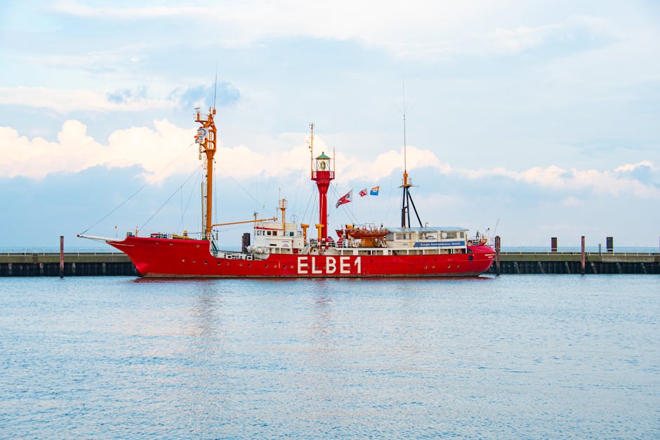 A vibrant red lightship Elbe 1 docked at Cuxhaven harbor under a bright sky.