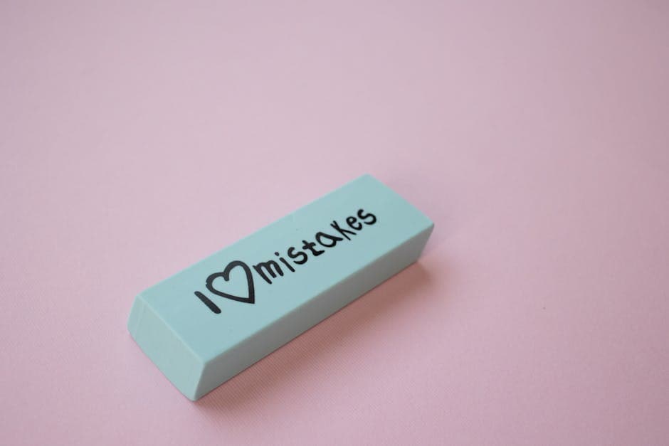 Close-up of a mint green eraser with 'I love mistakes' on a pink background.